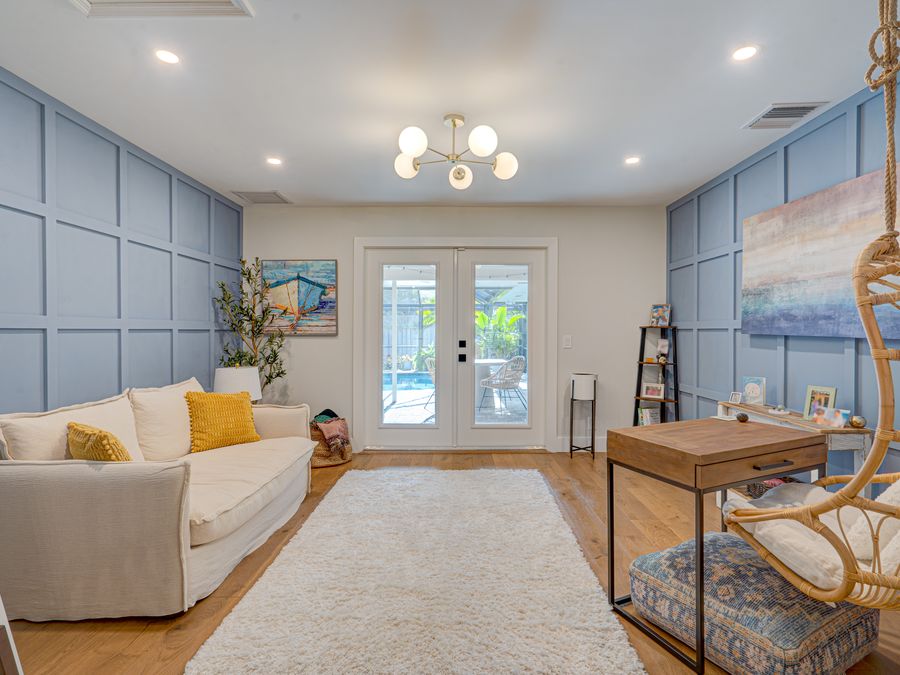 Coral Gables family room with blue panel walls and french doors to pool
